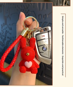 Detail of red resin bunny keychain with knitted texture and a pink heart on a leather strap