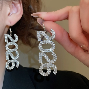 Dettaglio macro di orecchini argentati scintillanti con numero 2025 e cristalli
