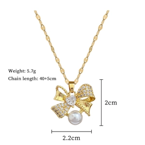 Detail of gold bow necklace pendant with heart crystal, pearl, and dimension markings