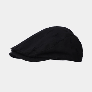 Detailed view of the vintage distressed black cotton flat cap with handmade frayed hole texture