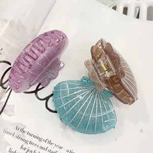 Détail de trois pinces à cheveux scintillantes en forme de coquillage sur magazine