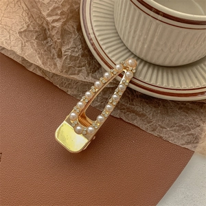 Detailed shot of golden pearl hair clip with rhinestones on a brown leather mat