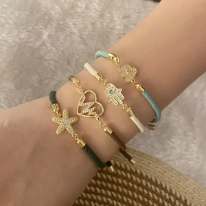 Set of four colorful woven bracelets with gold charms and rhinestone inlaid pendants