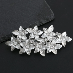 Close-up of vintage silver flower hair clip with sparkling rhinestones on black stone