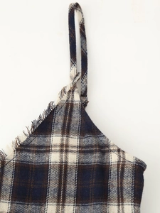 Close-up of blue plaid neckline with fringe trim and spaghetti straps on the dress