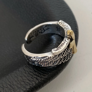 Macro shot of silver feather ring with golden cross and engraved freedom text