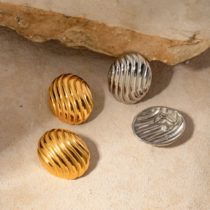 Détails de boucles d'oreilles ovales texturées dorées et argentées sur pierre