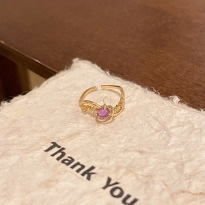 Macro shot of gold butterfly ring with purple zircon stone on a textured gift card