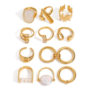 Set of 11 gold stainless steel rings with shell, pearl and zircon on white background
