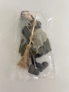 Detailed close-up of a Halloween witch doll with broom in transparent packaging
