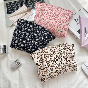 Detailed flat lay of corduroy leopard print makeup bags in pink, black, and beige colors