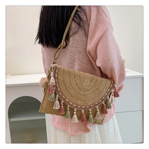Detail of bohemian straw bag featuring colorful tassels and woven ethnic pattern trim