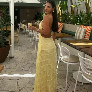 Detail of yellow backless pleated maxi dress with halter neck and textured fabric