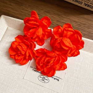 Macro view of 4 red fabric flower pendants with rich silk texture on a jewelry tray
