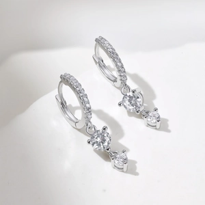 Macro shot of silver drop earrings featuring cubic zirconia heart pendants on hoops