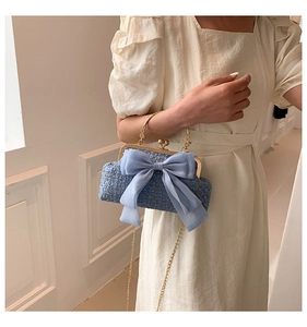 Détail d'un sac à main en tweed bleu avec grand nœud et élégante chaîne en métal doré