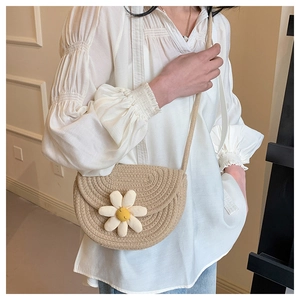 Dettaglio di borsa a sella intrecciata beige con margherita indossata da modella