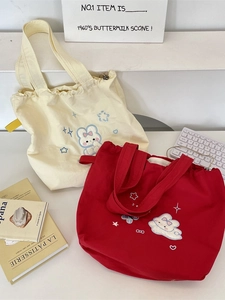 Cream and red canvas tote bags with cute bunny embroidery in a minimalist setting