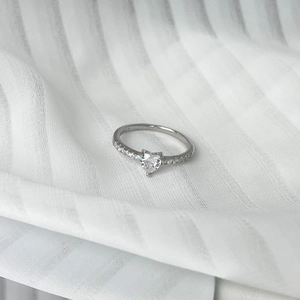 Close-up of S925 sterling silver ring with heart-shaped zircon on white fabric