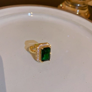 Macro detail of gold vintage flower ring with emerald green stone and small diamonds