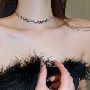 Dettaglio di una collana choker intrecciata con strass multicolori sulla clavicola
