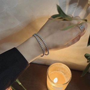 Close-up of double-layer silver tennis bracelet with cubic zirconia and a simple ring