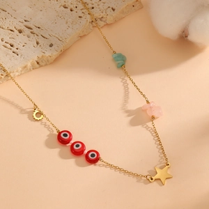 Detailed view of gold chain necklace with evil eye beads and natural stones on rock background