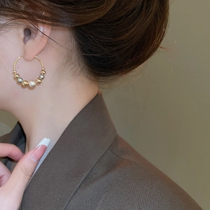 Detailed side view of pearl and gold bead twist hoop earrings worn by a model