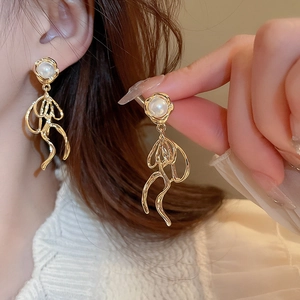 Detail of golden metal tassel earrings with pearls and elegant wavy ribbon drop pendant