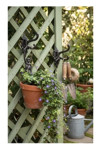 Detail of vintage cast iron hooks with monkey relief on a green wooden garden fence