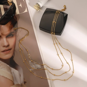 Detail of gold multilayer snake chain necklace with beads and lobster clasp on a magazine