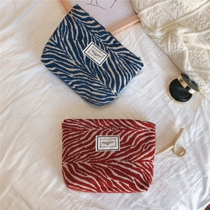 Flat lay of red and blue zebra pattern chenille makeup bags with TIME TO PARTY labels