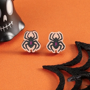 Detailed view of pink spider stud earrings styled with a skull and orange backdrop