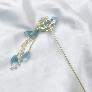 Detail of a vintage blue flower hairpin with pearl tassels on white silk background