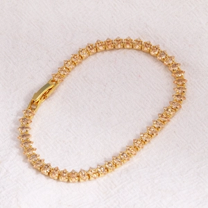 Detailed view of marquise-cut champagne zircons set in a golden knotted tennis bracelet
