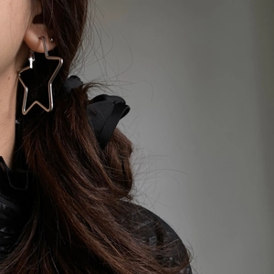 Close-up of minimalist silver star hoop earring on model with high metal luster