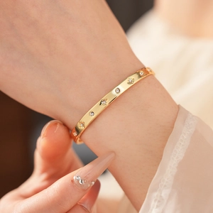 Gros plan d'un bracelet doré avec gravures d'étoiles et oxydes de zirconium au poignet