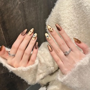 Handmade leopard print almond press-on nails with amber cat-eye effects and rhinestones