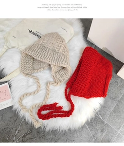 Détail du tricot épais des bonnets à oreilles beige et rouge avec tresses et glands
