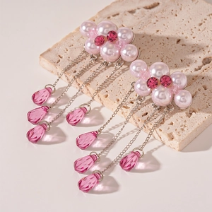 Close-up of pink pearl cloud earrings with crystal fringe on textured stone base