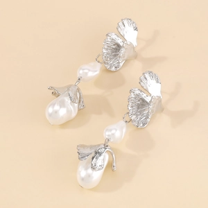 Macro shot of silver metal petal texture and baroque pearl detail on long earrings