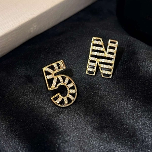 Detail of 18K gold plated asymmetric earrings with N and 5 shape white zircon inlays
