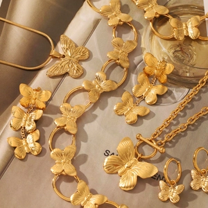 Flat lay of gold butterfly jewelry set including necklace and earrings on a magazine