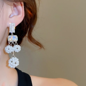 Detail of long silver tassel earrings with crystal studs and hollow pearl floral balls