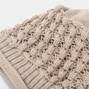Close-up of beige knit hat showing intricate hollow patterns and texture details