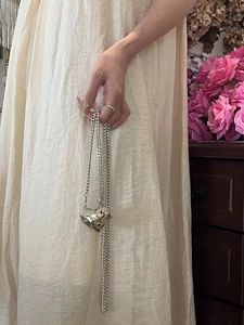 Silver liquid metal heart bag with cuban chain shown in a romantic setting