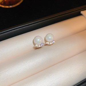 Macro shot of pearl stud earrings with zircon base on beige velvet jewelry display