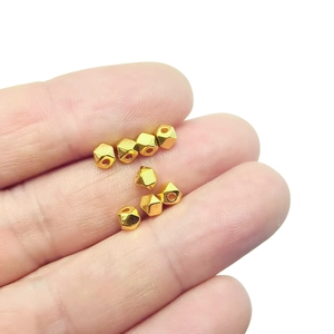 Handheld close-up of golden geometric polyhedral beads for DIY jewelry making projects