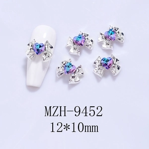 Close-up of 12x10mm alloy bow nail art charms with blue heart crystals on white nails