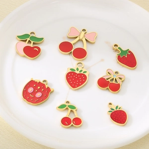 Macro di ciondoli a ciliegia e fragola in smalto rosso su un vassoio di ceramica bianca